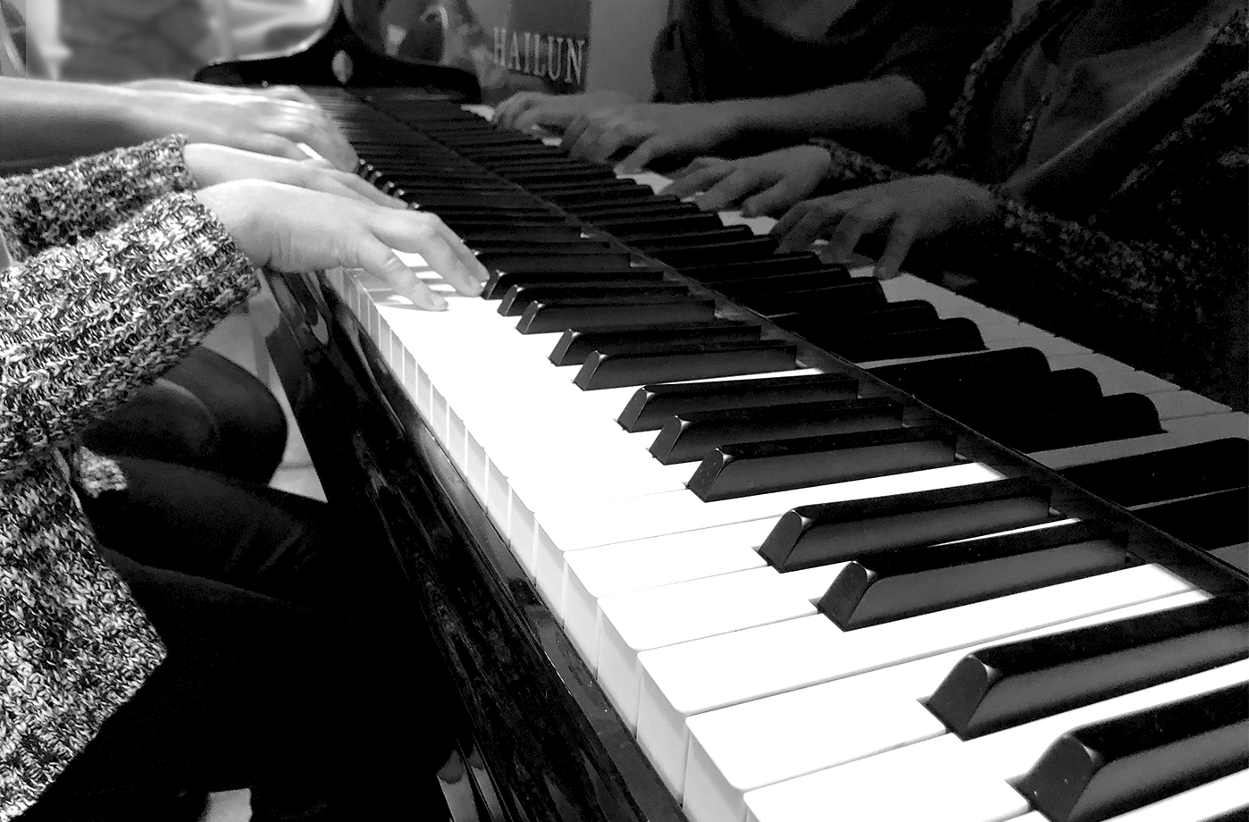 black and white photo of kids playing a piano